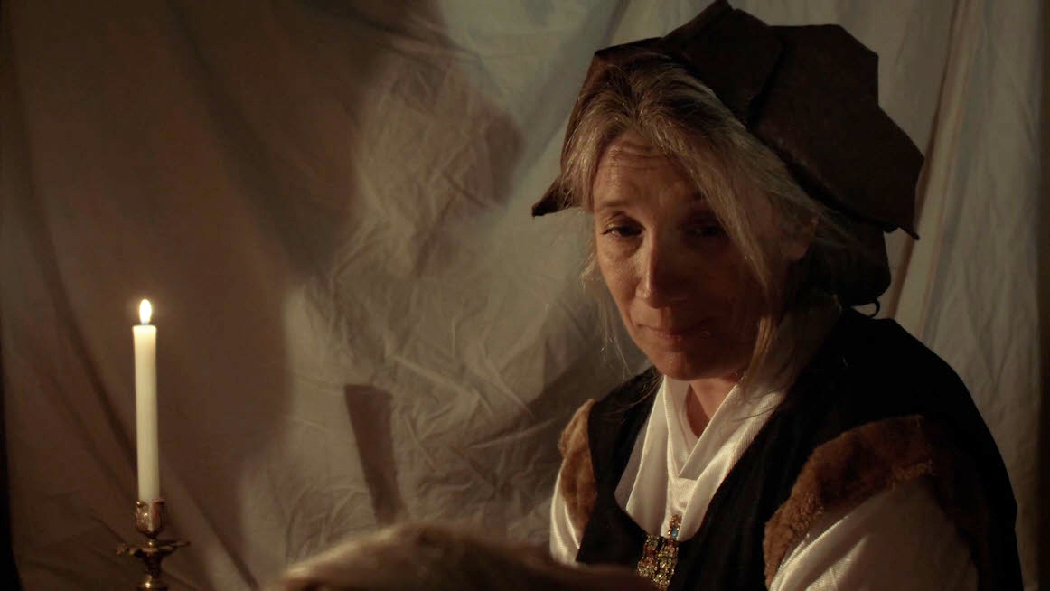 Mujer vestida de época junto a una vela en una escena íntima