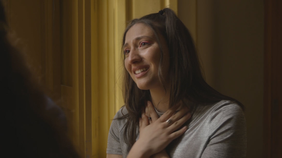 Mujer emocionada con la mano en el pecho en una escena íntima