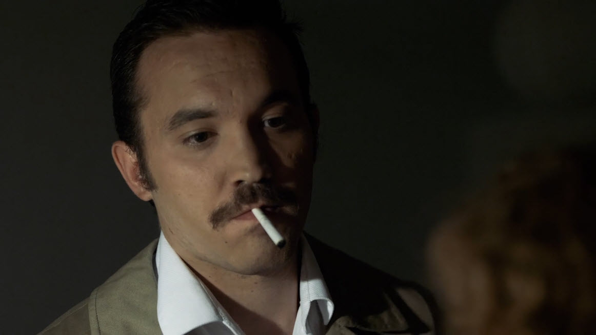 Hombre fumando en una escena oscura con atmósfera policial